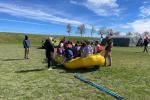 Students gather in an inflatable raft in a field with BLM staff standing nearby.