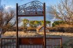 A gate to the Heritage Discovery Trail leads to a path along a grassy area of the Las Cienegas National Conservation Area.