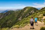 Three children hiking on a high mountain trail that overlooks an ocean.