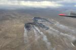 a wildfire from above with a straight line where it has burned next to a road