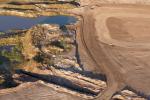 Aerial view of a barren landscape featuring small ponds, dirt mounds, and a cleared area, showing signs of excavation and mining activity.