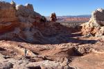 Swirling red and white sandstone formations under a clear blue sky in a desert landscape.