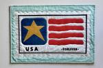 Quilted fabric artwork resembling a USA postage stamp with a gold star, red stripes, and "USA" and "FOREVER" text.