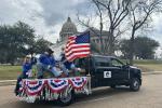 A group of people sit on a truck bed decorated with an American flag and bunting. 