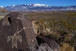 A petroglyph atop a hill with a mountain in the background.