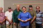 Seven fisheries volunteers stand together with the program leader in a meeting room during a volunteer appreciation event.