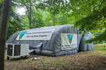 Inflatable cave and karst education exhibit in a wooded area, labeled Bureau of Land Management and Ft. Stanton–Snowy River Cave.