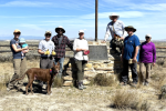 group of blm staff and volunteers stand for photo in front of marker with blue sky