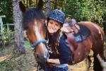 Woman standing while cradling horse's head in her arms. 