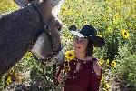 Woman with burro in field of flowers. 