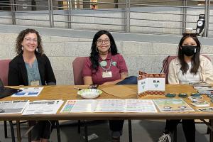 Three people sitting at a table with outreach materials