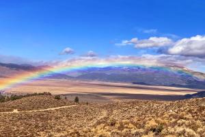 A rainbow spanning a section of land and a mountain range in the background.