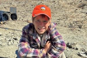 Touren Pope poses for a photo with the fossilized turtle he discovered on BLM with a blue sky