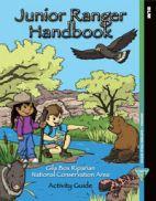 The cover of the Junior Ranger handbook showing two kids by a stream with a hawk overhead and a javelina, a beaver, and a Gila monster.