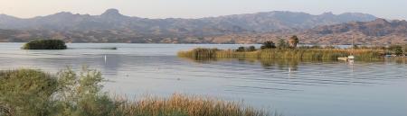 a lake with grassy islands and distant mountains