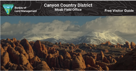 Moab Visitor Guide brochure cover with a scene of sandstone fins and snow-capped mountains behind them