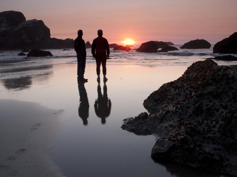 Two men on a beach at sunset