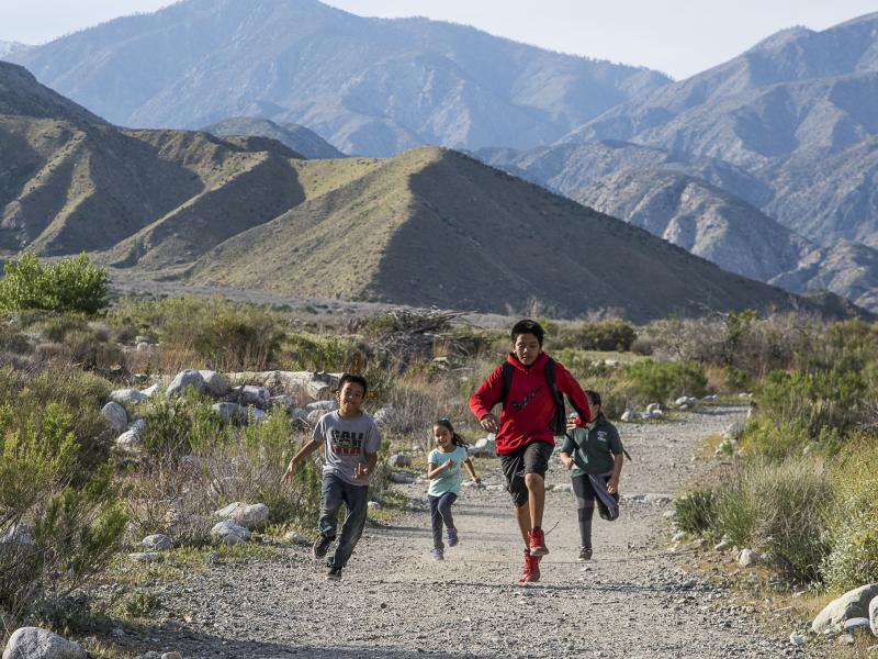 Kids running on a trail with mountains in the distance