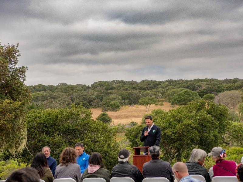 BLM Central Coast Field Manager Zachary Ormsby speaking at podium outside under cloudy skies