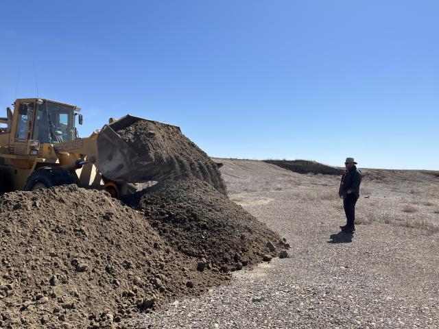A man watches a dozer move dirt and rocks.