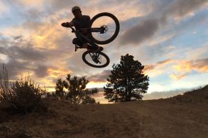 Photo: sihouetted mountain biker goes airborne with sunset in background